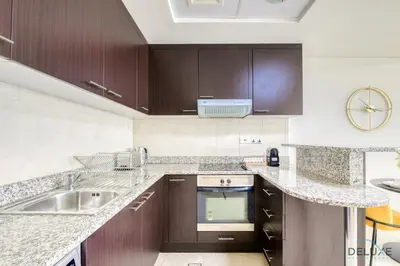 a kitchen with wooden cabinets and a sink at Refreshing Studio at Sky Gardens DIFC by Deluxe Holiday Homes in Dubai