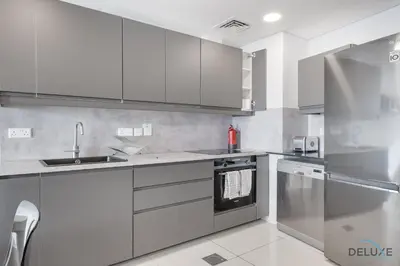 a kitchen with white cabinets and stainless steel appliances at Scenic 1BR at Ocean Heights Dubai Marina by Deluxe Holiday Homes in Dubai
