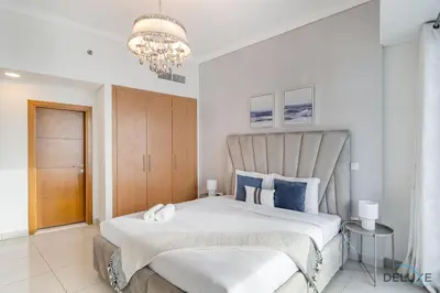 a bedroom with a large bed and a chandelier at Scenic 1BR at Ocean Heights Dubai Marina by Deluxe Holiday Homes in Dubai