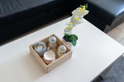 a white table with a vase of flowers and a vase of flowers at White Sage - Luxurious Studio in JLT With City Skyline View in Dubai