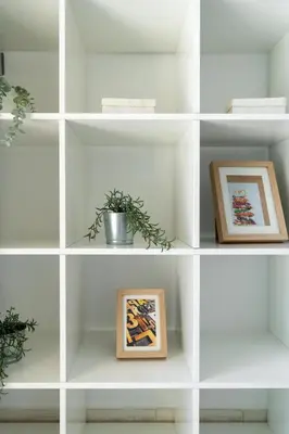a white shelving unit with paintings and plants on it at White Sage - Luxurious Studio in JLT With City Skyline View in Dubai