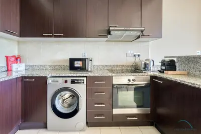 a kitchen with a washing machine and a microwave at Jubilant 1BR at Sky Gardens DIFC by Deluxe Holiday Homes in Dubai