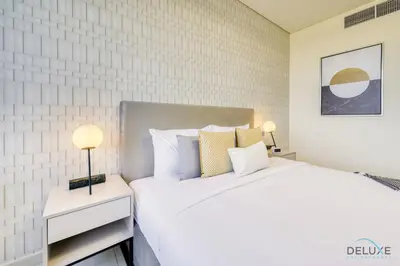 a white bedroom with a large bed and two lamps at Jubilant 1BR at Sky Gardens DIFC by Deluxe Holiday Homes in Dubai