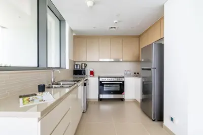 a kitchen with white cabinets and a stainless steel refrigerator at GuestReady - Luxury l Sea Views Oasis in Dubai