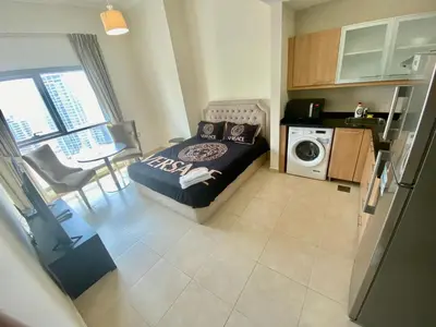 a small bedroom with a bed and a kitchen at Cosy Studio in Marina in Dubai