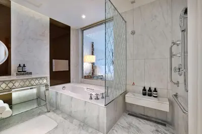 a bathroom with a tub and a shower with a window at Waldorf Astoria Dubai Palm Jumeirah in Dubai