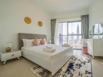 a white bedroom with a large bed and a large window at Glamorous Apartment Facing Burj Khalifa in Dubai