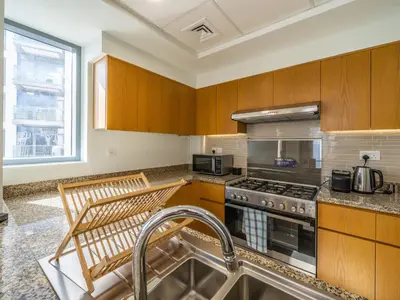 a kitchen with wooden cabinets and a stove top oven at Glamorous Apartment Facing Burj Khalifa in Dubai