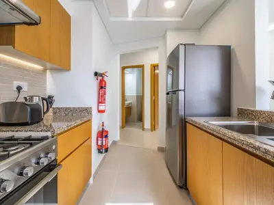 a kitchen with wooden cabinets and a stainless steel refrigerator at Glamorous Apartment Facing Burj Khalifa in Dubai
