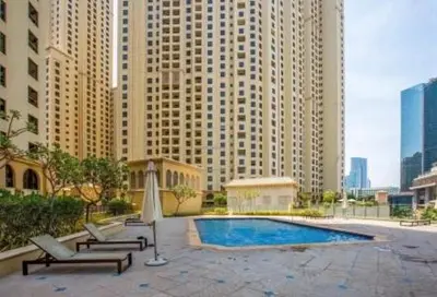 a pool with lounge chairs and an umbrella and buildings at 300m From The Beach - JBR Apartment with Sea & Dubai Eye Views in Dubai