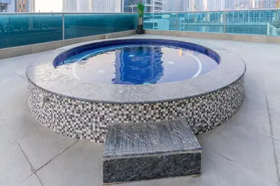 a circular pool with a bench in a building at Family-Sized 4BR Pool, Jacuzzi & Gym in Dubai