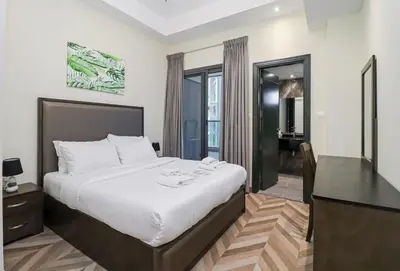 a hotel room with a large bed and a desk at Spacious 4BR En-Suite Apt I Gym, Pool & Parking in Dubai