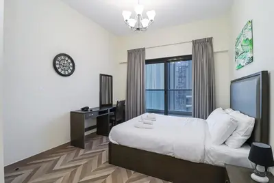 a bedroom with a bed and a desk and a window at Spacious 4BR En-Suite Apt I Gym, Pool & Parking in Dubai