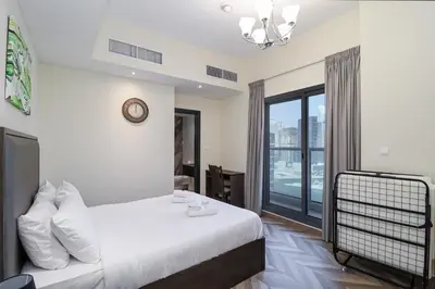 a bedroom with a bed and a large window at Spacious 4BR En-Suite Apt I Gym, Pool & Parking in Dubai