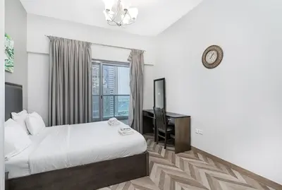a bedroom with a bed and a desk and a window at Cozy Family Apt Canal Vista Near Dubai Mall in Dubai