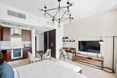 a living room with a large television and a kitchen at Silkhaus cozy central studio in Downtown in 29 Boulevard in Dubai