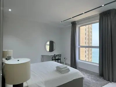a bedroom with a white bed and a large window at STYLISH 2 BEDROOM SERVICE APARTMENT with SEA VIEW in Dubai