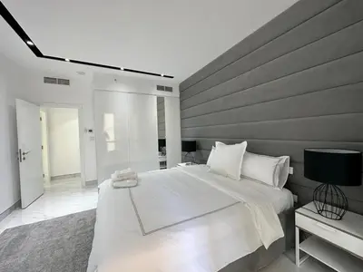 a bedroom with a large white bed and a table at STYLISH 2 BEDROOM SERVICE APARTMENT with SEA VIEW in Dubai