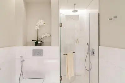 a white bathroom with a shower with a glass door at The Smart Concierge - Palm tower in Dubai