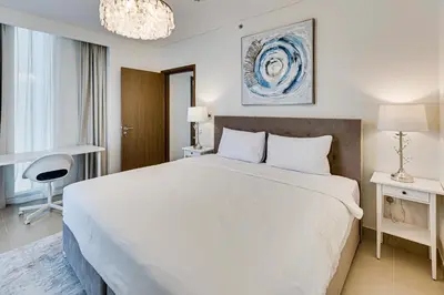 a bedroom with a large white bed and a chandelier at Sea View 2BD in new 52 42 tower Dubai Marina in Dubai