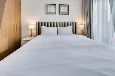 a large white bed in a bedroom with two lamps at Sea View 2BD in new 52 42 tower Dubai Marina in Dubai