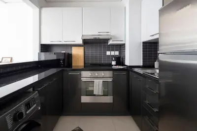 a kitchen with stainless steel appliances and black cabinets at Frank Porter - Silverene Tower B in Dubai