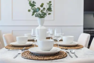 a table with plates and glasses and a vase at GuestReady - Magnificent heart of Downtown in Dubai