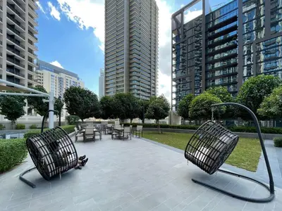 two chairs and tables in a park with tall buildings at GuestReady - Magnificent heart of Downtown in Dubai