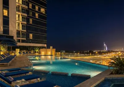 a large swimming pool at night with buildings at Avani Palm Burj-AlArab View from the pool in Dubai