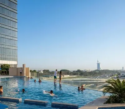 a group of people in a swimming pool on the roof of a building at Avani Palm Burj-AlArab View from the pool in Dubai