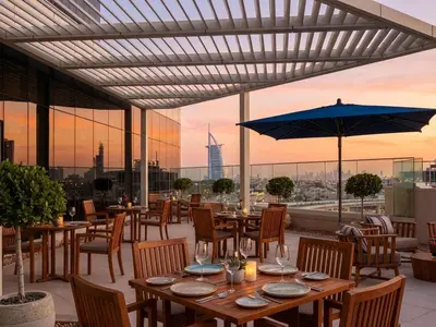 a restaurant with tables and chairs and a view of the city at Avani Palm Burj-AlArab View from the pool in Dubai