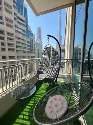 a balcony with two chairs and a table and a swing at 2BR Dubai Burj View Downtown Skyline with Pool, Gym, & Parking in Dubai