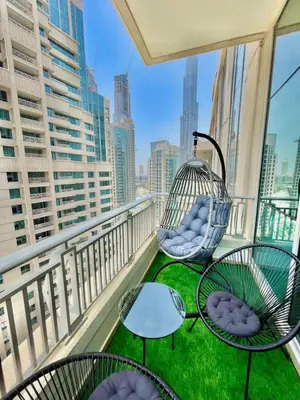 a balcony with chairs and tables and a swing at 2BR Dubai Burj View Downtown Skyline with Pool, Gym, & Parking in Dubai