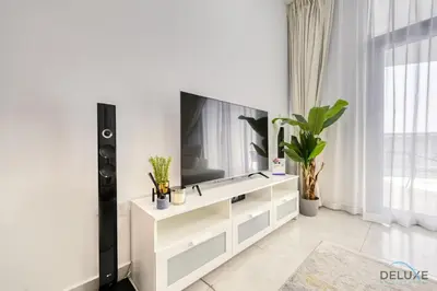 a living room with a television on a white dresser at Urban 1BR at Binghatti Stars Dubai Silicon Oasis by Deluxe Holiday Homes in Dubai