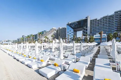 a row of white chairs and umbrellas on a beach at Daniels Stunning 2BR with Full Sea View at Five in Dubai