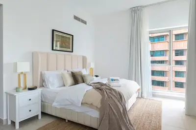 a white bedroom with a large bed and a window at HiGuests - Amazing Apartment overlooking Burj Khalifa! in Dubai
