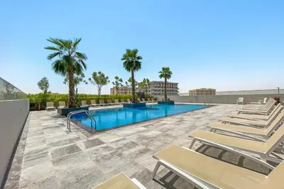 a swimming pool with lounge chairs and palm trees at Luxurious 2BR - Fully Upgraded - High-end facilities in Dubai