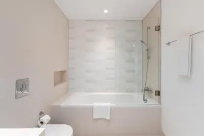 a white bathroom with a tub and a shower at Sunrise Bay, Emaar Beachfront Dubai Harbour - Mint Stay in Dubai