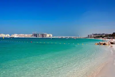 a beach with blue water and buildings in the background at Modern 2BR in the Heart of Dubai Marina in Dubai