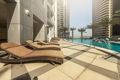 a pool with lounge chairs next to a building at Modern 2BR in the Heart of Dubai Marina in Dubai