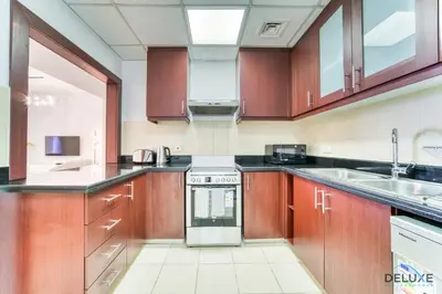 a large kitchen with wooden cabinets and a sink at Impeccable 2BR at Bahar 2 JBR by Deluxe Holiday Homes in Dubai