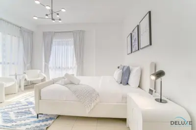 a white living room with a white couch and a table at Impeccable 2BR at Bahar 2 JBR by Deluxe Holiday Homes in Dubai