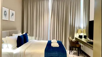 a hotel room with a bed and a desk and a window at Vacay Lettings - Damac Prive studio in Dubai