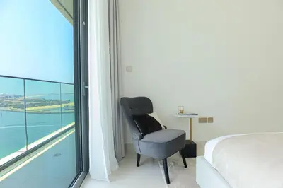 a bedroom with a chair in front of a window at HiGuests - Superlative apt with private beach access in Dubai