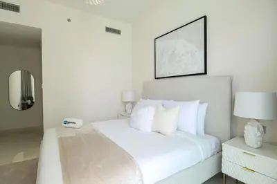 a white bedroom with a bed with white pillows at HiGuests - Superlative apt with private beach access in Dubai