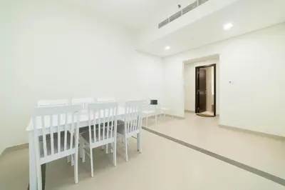 a white dining room with white chairs and a table at OYO 589 Najma Tower, Two bedrooms Apartments, Sports City in Dubai