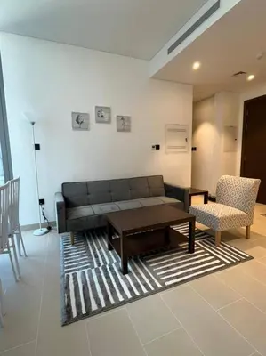 a living room with a couch and a table and chairs at OYO 887 Home A1607 Sobha Creek Vistas - 1BR in Dubai