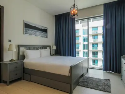 a bedroom with a bed and a large window at OYO 755 Home Sobha Greens in Dubai