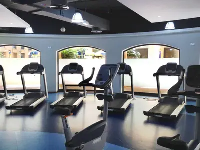 a gym with several treadmills in a room with windows at La Buena Vida Holiday Homes, Luxe, 3BR with, full kitchen, Marina View, by JBR Beach, Tram & Marina in Dubai