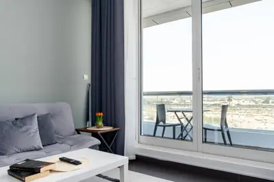 a living room with a couch and a large window at Vacay Lettings - Silicon Oasis Budget Friendly Studio in Dubai